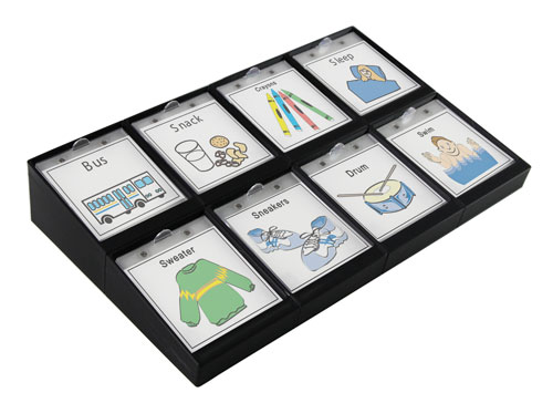 An angled rectangular communication device with a grid of large square buttons showing illuminated icon targets.