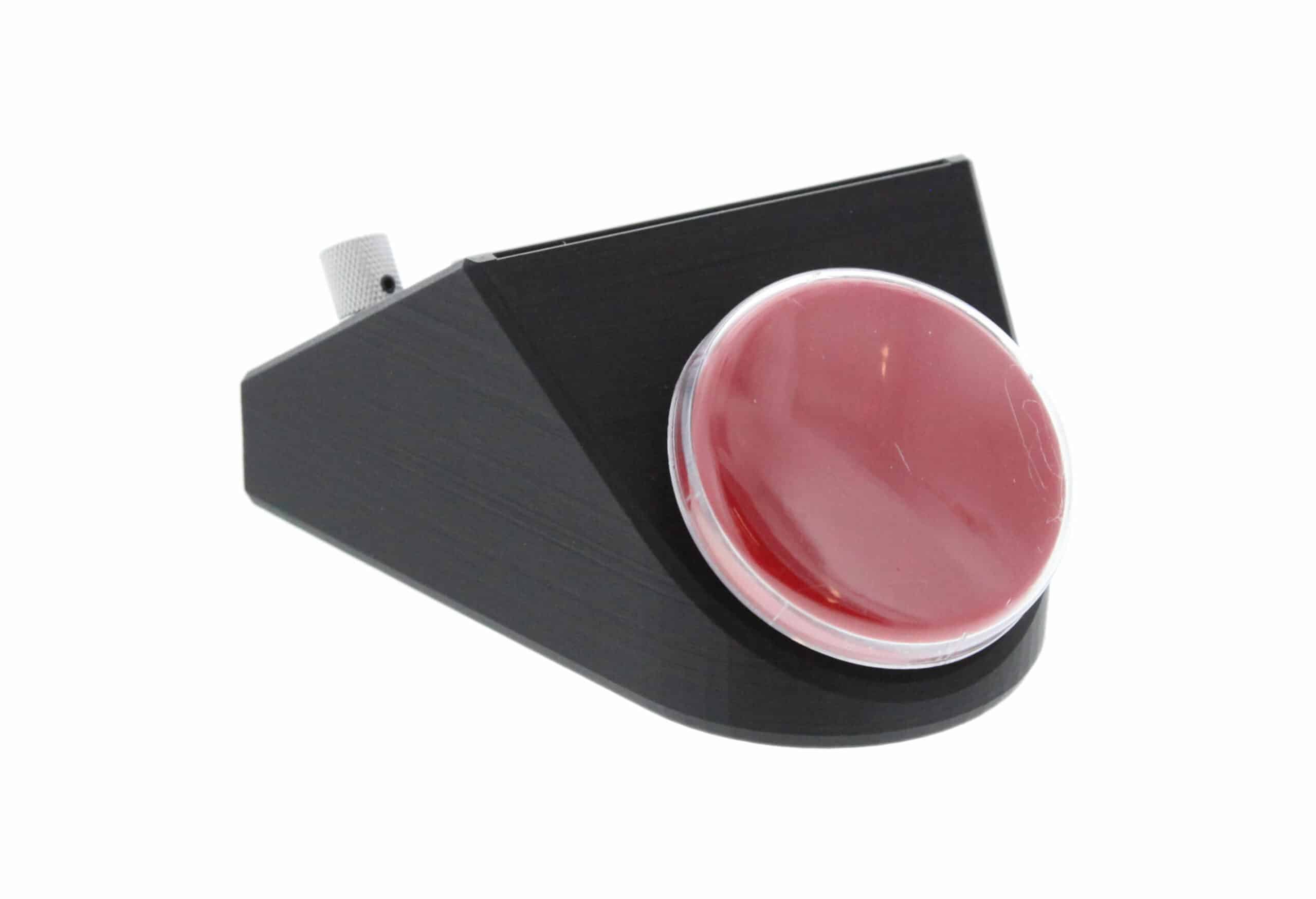 A small square communicator with a large round red activation switch plate under a clear cover.