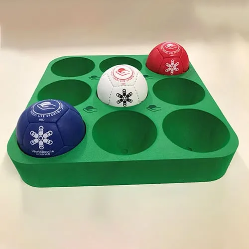 A green foam boccia tray with nine round recesses, three holding red, white and blue balls.