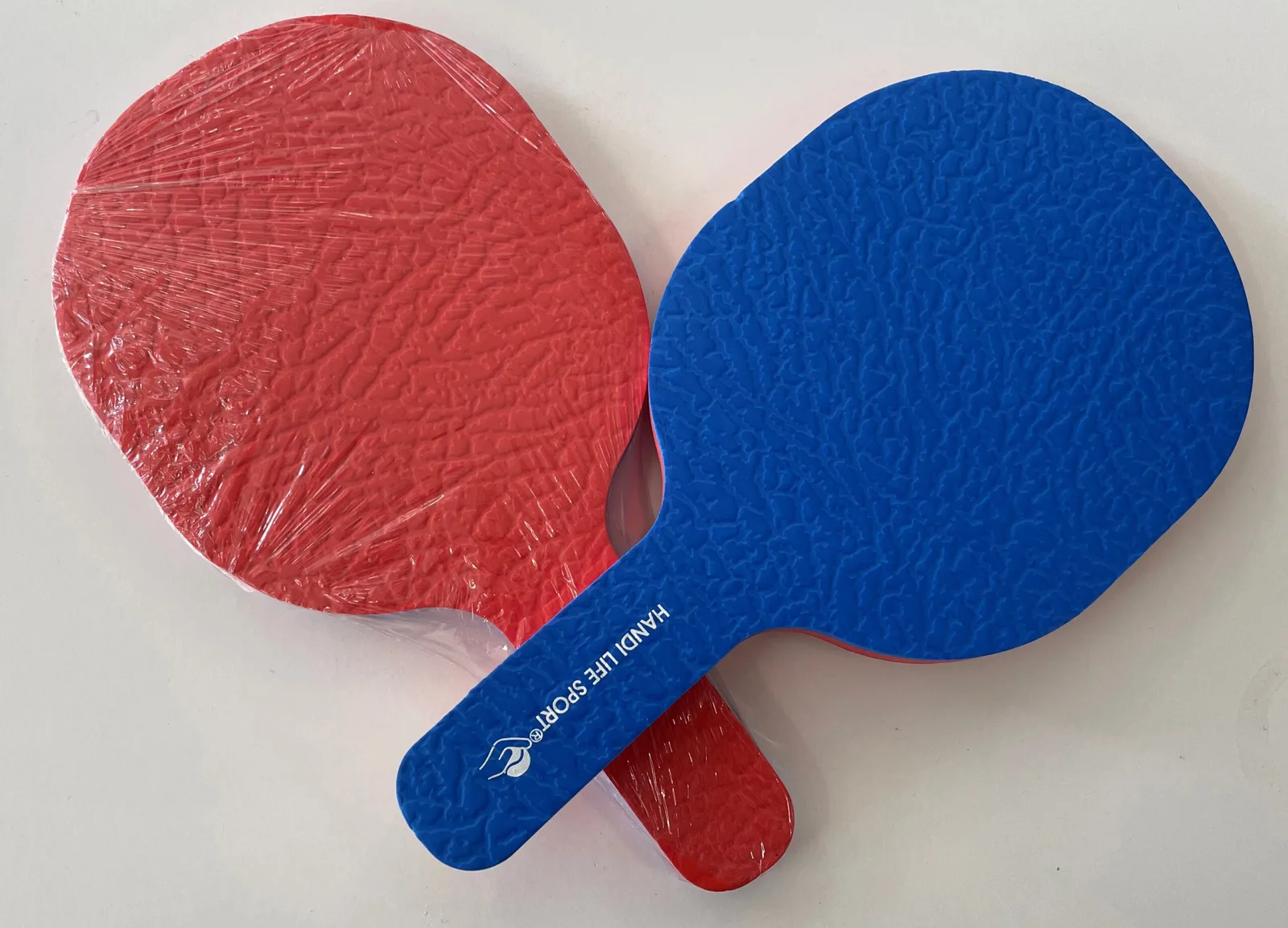 Two boccia referee paddles, one red and one blue, with textured faces.