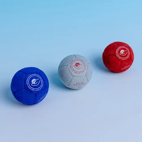 Three suede boccia balls in blue, natural grey and red with a soft matte texture.