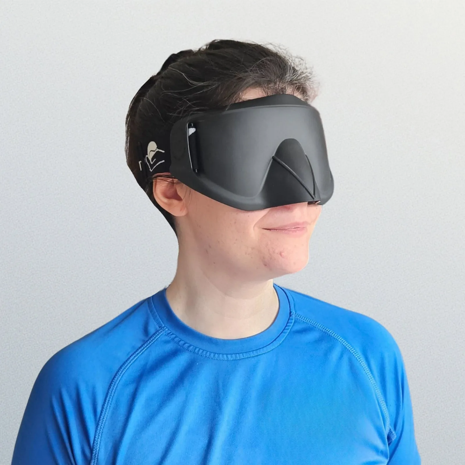 A person wearing a black blackout blind-sports mask with a moulded nose guard.