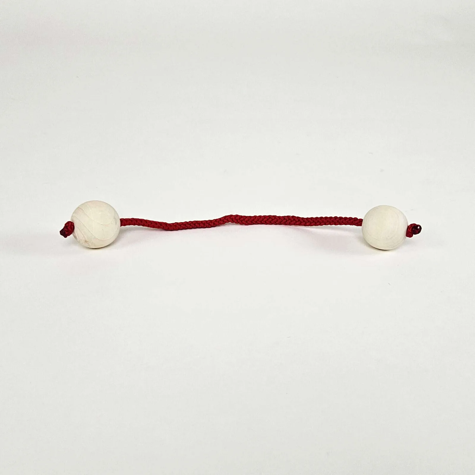 Two pale wooden balls connected by a short red woven cord.