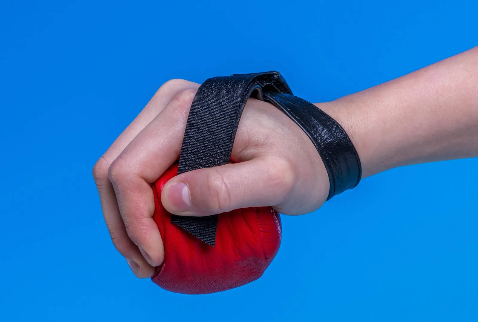 A hand gripping a red Trimmy hand weight held on by a black velcro strap.