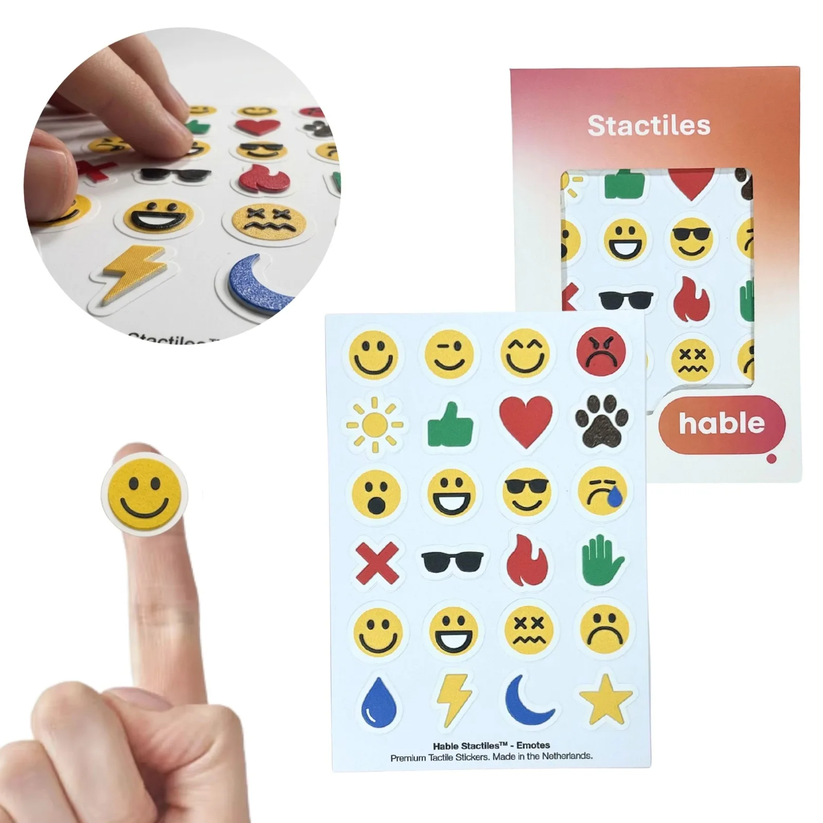 The Hable Stactiles Emojis set: a white sheet of raised emoji stickers including smiling, winking, surprised, sad and dizzy faces, a sun, a green thumbs-up, a red heart, a paw print, sunglasses, a flame, a hand, a water drop, lightning, a moon and a star, shown with its orange box. A fingertip holds a single yellow smiley and an inset shows fingers feeling the stickers.
