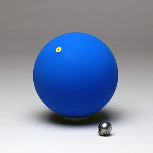 A matt blue rubber ball with a small yellow valve disc, with a chrome jingle bell resting beside it.