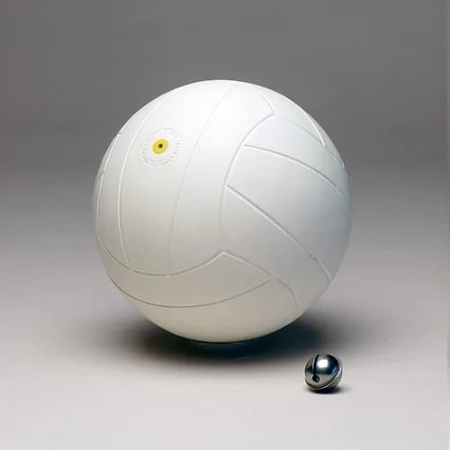 A white rubber football with moulded panel seams and a yellow valve disc, with a chrome jingle bell beside it.
